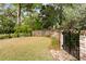 Beautiful backyard with green grass, a brick wall, mature trees, and iron gate at 333 W Confederate Cir, Charleston, SC 29407