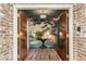 Foyer with brick-lined entryway leading to a serene space featuring mural, hardwood floors, table, and flowers at 333 W Confederate Cir, Charleston, SC 29407