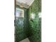 A walk-in shower features green tile, updated fixtures, and a small window to allow natural light into the space at 333 W Confederate Cir, Charleston, SC 29407