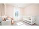 Serene bedroom with a crib, white wainscoting, and a comfortable wicker chair next to a writing desk at 339 Pine Crest View Dr, Summerville, SC 29486