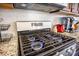 Close-up of a modern stainless steel gas stovetop with blue flames, set against a stylish tiled backsplash at 403 Fox Sparrow Ct, Summerville, SC 29486