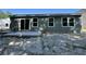 Back exterior features gray siding, windows, and a concrete patio in a sandy lot at 5031 Scow Ct, Summerville, SC 29485
