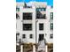 Stunning white brick townhome featuring multiple balconies, large windows, and a well-manicured front yard at 508 Helmsman St, Charleston, SC 29492