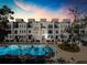 Modern multi-Gathering homes with large swimming pool and surrounding lounge area at dusk at 508 Helmsman St, Charleston, SC 29492