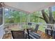 Relaxing screened porch with wooded view features a table with seating for four, and string lights, ideal for outdoor dining and entertaining at 521 Sanders Farm Ln, Wando, SC 29492