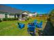 Well-maintained backyard with vibrant green lawn, wooden fence, and a cozy fire pit surrounded by blue Adirondack chairs at 521 Yellow Tower Ter, Charleston, SC 29412