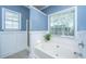 Bright blue bathroom features a large soaking tub near a window, wainscotting, and tile floors at 522 Antebellum Ln, Mount Pleasant, SC 29464
