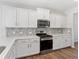 Modern kitchen with white cabinetry, stainless steel appliances, and stylish backsplash for a sleek and functional space at 525 Purple Finch Rd, Summerville, SC 29486