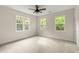 An empty bedroom with three windows, neutral walls, and carpeted floors at 5950 Kelseys Mill Rd, Ravenel, SC 29470