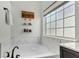 This bathroom offers a luxurious soaking tub under a window with a garden view and marble tile surround at 9670 Pebble Creek Blvd, Summerville, SC 29485