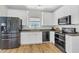 Modern kitchen features white cabinets, black stainless steel appliances, and hardwood flooring at 9670 Pebble Creek Blvd, Summerville, SC 29485