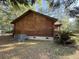 Side view of a log cabin featuring a visible HVAC system and lush green vegetation surrounding the property at 1020 Welles Ln, Walterboro, SC 29488