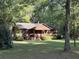 Scenic log cabin nestled among mature trees, featuring a charming front porch and a well-manicured lawn at 1020 Welles Ln, Walterboro, SC 29488