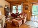 Bright living space with wood floors, a classic writing desk, and armchair situated near a sunlit window and porch door at 1020 Welles Ln, Walterboro, SC 29488
