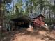 Exterior shot of the red outbuilding with storage, in a lush wooded setting at 1020 Welles Ln, Walterboro, SC 29488