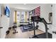 Bright home gym with hardwood floors, weight rack, treadmill, TV, and an American flag at 1167 Mossy Rock Dr, Summerville, SC 29485