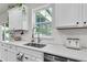 Close up of a kitchen sink with quartz countertops and white cabinets with greenery accents at 1167 Mossy Rock Dr, Summerville, SC 29485