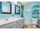Bright bathroom with double vanity, tile floors, blue walls, tub, and open shelving for towels at 138 Avalon Rd, Summerville, SC 29483