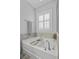 Oversized white soaking tub features tile surround and a view to a shuttered window at 1488 Croaton Crsg, Mount Pleasant, SC 29466