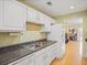 Traditional kitchen with white cabinets, dark countertops, and views into the living room at 1516 Blaze Ln, Charleston, SC 29412