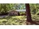 Quaint brick home with lush lawn, shaded by mature trees, offering a serene setting at 1521 Camp Rd, Charleston, SC 29412
