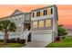 Well-lit townhouse showcases a garage, neat landscaping, and classic black shutters under a vibrant twilight sky at 207 Winding River Dr, Johns Island, SC 29455