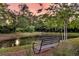 Bench overlooking a tranquil pond with mature trees, creating a serene outdoor space at 2131 Pentland Dr, Charleston, SC 29412