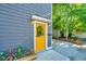Close up of home's stylish yellow front door with modern lighting and beautiful landscaping at 2130 Weaver St, Charleston, SC 29403