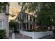 Inviting two-story home at dusk featuring a white picket fence, brick driveway, and warm exterior lighting at 23 Savage St, Charleston, SC 29401