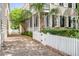 Brick driveway leading to a charming home with a white picket fence and lush green landscaping at 23 Savage St, Charleston, SC 29401