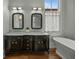 Bathroom with double vanity, marble countertop, dark cabinets, soaking tub, and windows with natural light at 24 Chalmers St, Charleston, SC 29401