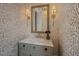 Charming powder room with patterned wallpaper, sconce lighting, and marble-top vanity at 24 Chalmers St, Charleston, SC 29401