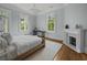 Bright bedroom with a bed, marble fireplace, two large windows, and hardwood floors at 24 Chalmers St, Charleston, SC 29401
