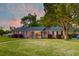 Traditional brick home with a well-manicured lawn, symmetrical windows, and black shutters at dusk at 2506 Birkenhead Dr, Charleston, SC 29414