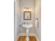 Stylish pedestal sink with a decorative mirror and designer light fixtures, and hardwood floors at 2640 Crooked Stick Ln, Mount Pleasant, SC 29466