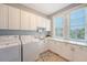 Well-lit laundry room with storage cabinets, modern washer/dryer, sink, and bright windows at 2640 Crooked Stick Ln, Mount Pleasant, SC 29466