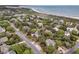 An aerial view shows a neighborhood with mature trees and a glimpse of the beach in the distance at 3635 Pompano Ct, Seabrook Island, SC 29455