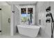 Modern bathroom features a soaking tub with marble tile and a window view at 3635 Pompano Ct, Seabrook Island, SC 29455