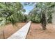 Inviting wooden walkway is surrounded by tropical trees, lush foliage, and ground lighting at 3635 Pompano Ct, Seabrook Island, SC 29455