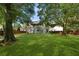 Expansive and private backyard with mature trees, lush green grass, and a charming home exterior at 5418 Percival Ln, Charleston, SC 29420