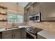 Updated kitchen features painted cabinets, stainless steel appliances, brick backsplash, and quartz countertops at 5418 Percival Ln, Charleston, SC 29420