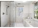 Bright bathroom featuring a glass-enclosed shower, soaking tub, and natural light at 76 Radcliffe St, Charleston, SC 29403