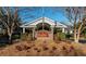 Beautiful clubhouse entrance with brick signage and manicured landscaping on a sunny day at 8642 W Fairway Woods Dr, North Charleston, SC 29420