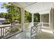 Inviting front porch with painted white railings, ceiling, and chairs, surrounded by lush landscaping and mature trees at 9 24Th Ave, Isle of Palms, SC 29451