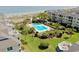 Stunning aerial view of a resort-style community with a pool, lush landscaping, and direct beach access at 9000 Palmetto Drive # D-304, Isle of Palms, SC 29451
