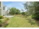 Sprawling backyard with lush green grass, a stone patio, and a serene backdrop of trees and natural foliage at 1006 Basin Ln, Johns Island, SC 29455