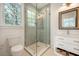 Bathroom featuring a glass shower, white vanity, blue tiled shower, and window providing natural light at 1006 Basin Ln, Johns Island, SC 29455