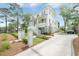 Charming white home featuring a welcoming front porch, lush landscaping, and a concrete driveway leading to a garage at 1006 Basin Ln, Johns Island, SC 29455