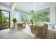 Inviting screened-in porch features cozy wicker seating, a ceiling fan, and serene views of the surrounding trees at 1006 Basin Ln, Johns Island, SC 29455