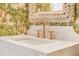 Close-up of a modern sink and faucet with a palm print wallpaper backdrop at 1006 Basin Ln, Johns Island, SC 29455